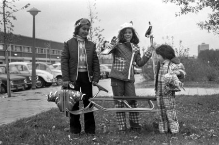 Drie kinderen, voorzien van wintersport attributen, showen de kleding, Bestanddeelnr 926-8084