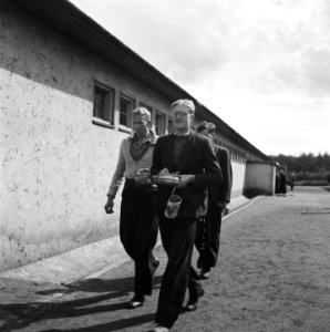 Drie mannen lopen langs een barak, met messtins en bestek, Bestanddeelnr 900-4828