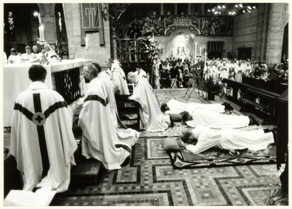 Drie priesters, Nico van der Peet, broeder Piet Lindner en Han Snel liggen plat op de grond tijdens hun wijding in de St. Bavo Kathedraal. NL-HlmNHA 54031903