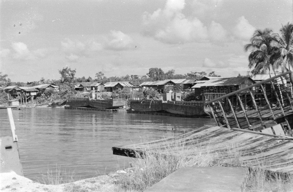 Dorp aan een rivier De huizen hebben golfplaten daken Langs de rivier oude la, Bestanddeelnr 438-5-6