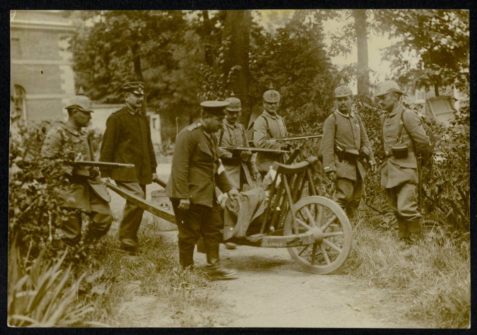 Duitse militairen vervoeren een gewonde soldaat op een kruiwagen in een stedelij, Bestanddeelnr 158-0674