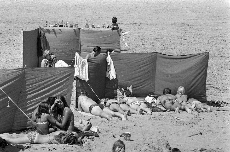 Drukte op Scheveningse strand rijtje zonnebaders achter windscherm, Bestanddeelnr 927-3399