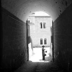 Doorkijk door poort waarin een man met emmer en touw aan het hijsen is, Bestanddeelnr 255-2453