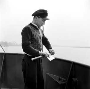 Eerste stuurman Hans wikkelt een bericht voor de wal om een werpstok, Bestanddeelnr 254-1331