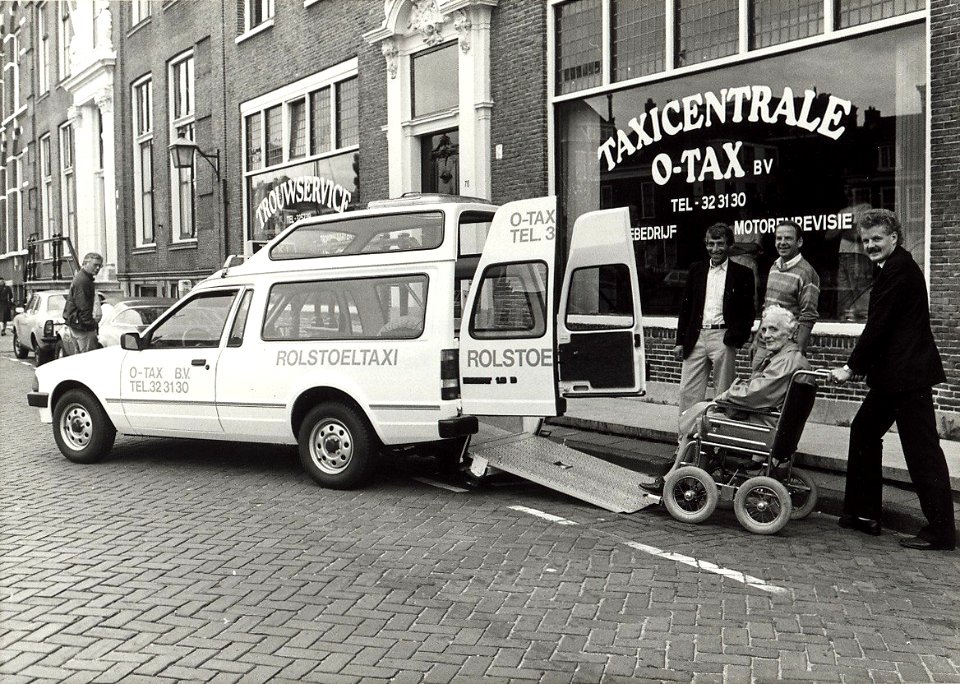 Eerste rolstoeltaxi bij O-TAX aan de Nieuwe Gracht 78. Aangekocht in 1987 van United Photos de Boer bv. - Negatiefnummer 25446 k 18 A. - Gepubliceerd in het Haarlems Dagblad van 26.08.1985, NL-HlmNHA 54010752
