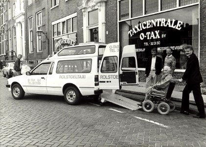 Eerste rolstoeltaxi bij O-TAX aan de Nieuwe Gracht 78. Aangekocht in 1987 van United Photos de Boer bv. - Negatiefnummer 25446 k 18 A. - Gepubliceerd in het Haarlems Dagblad van 26.08.1985, NL-HlmNHA 54010752