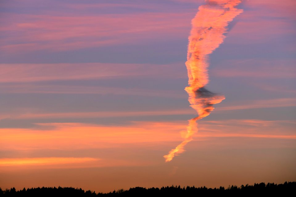Elongated smoke plume from the oil refinary crossing clouds at sunset 2