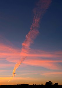 Elongated smoke plume from the oil refinary crossing clouds at sunset 1
