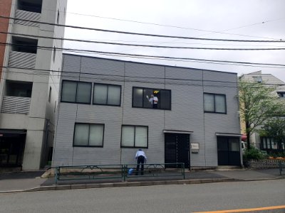Employees cleaning windows and at the front of the company, in the morning