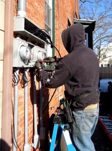 Electrician using screwdriver to install external panels for meters in NJ