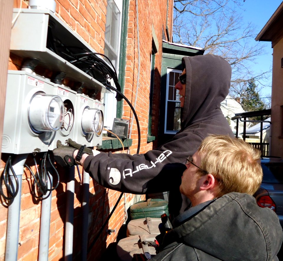 Electricians installing separate panels for meters on multifamily house in NJ