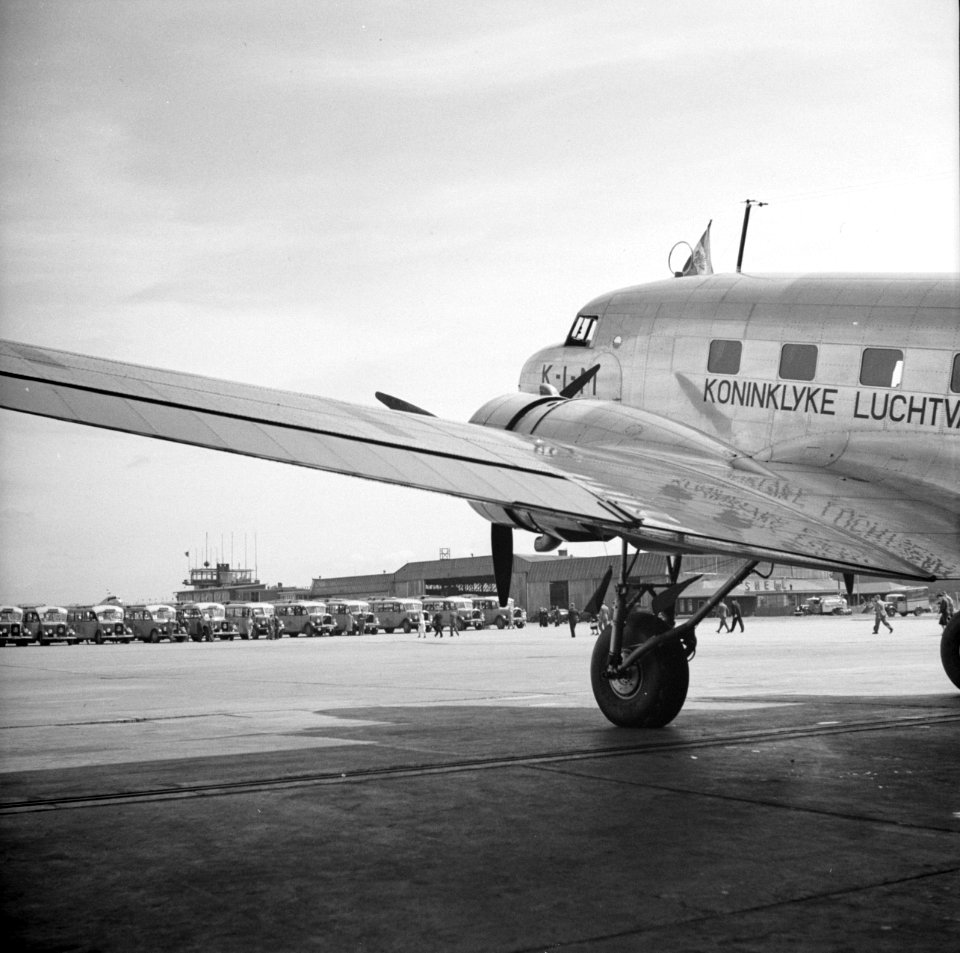 Een KLM DC-3 staat geparkeerd op luchthaven Schiphol terwijl reizigers naar de w, Bestanddeelnr 254-2414