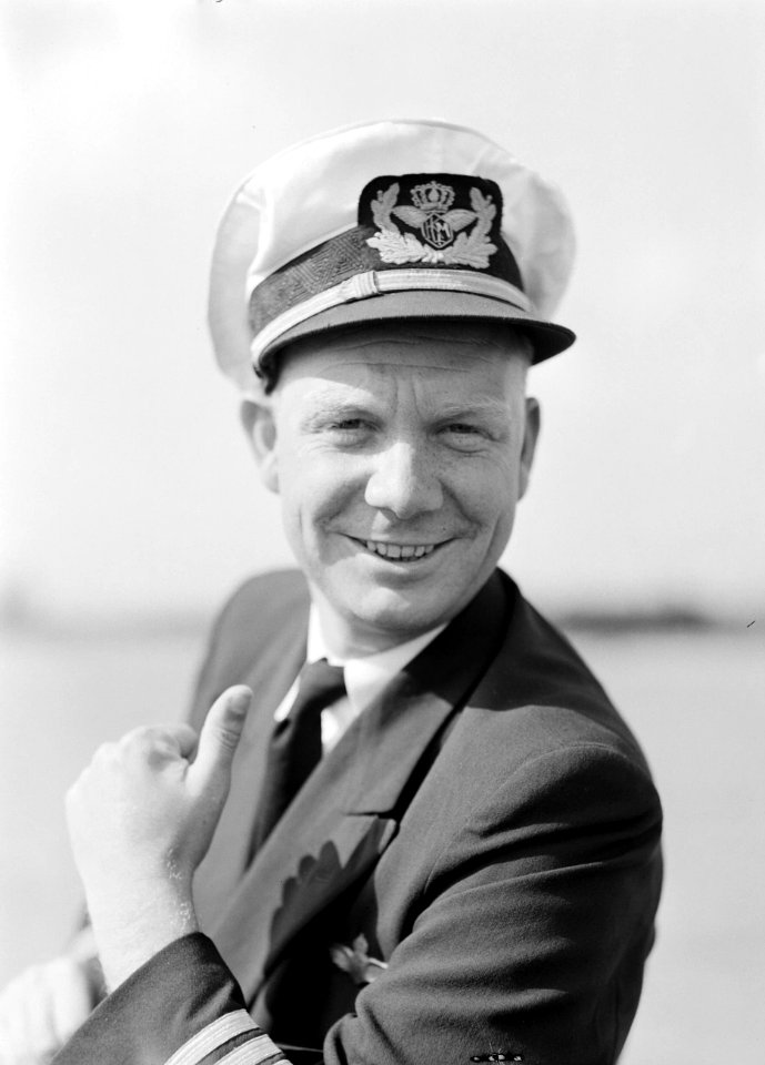 Een KLM stewardess poseert voor een vliegtuig met het Flying Dutchman embleem, Bestanddeelnr 255-8957