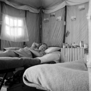 Een lid van het Vrouwelijk Hulp Korps op bed in haar tent in Ataka, Bestanddeelnr 255-6918