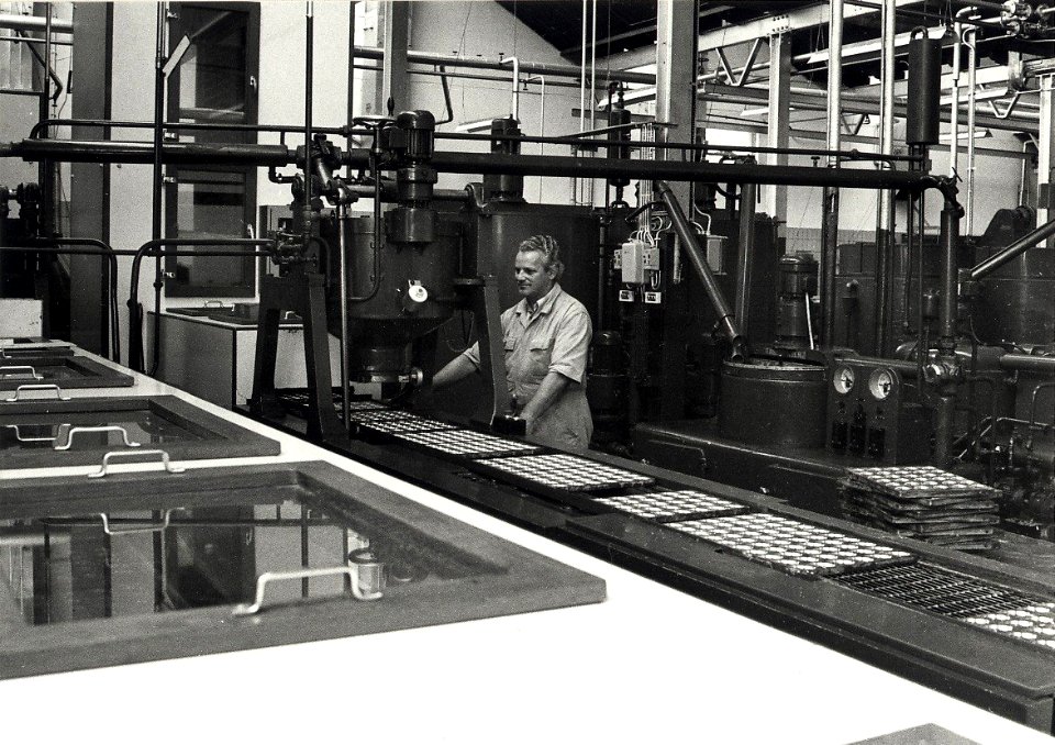 Een kijkje in de Union-fabriek vaan de Paul Krugerkade, waar aan de lopende band door Dhr. Beringen chocolaatjes gegoten worden. Aangekocht in 1981 van fotograaf C. de Boer. - Negatiefnummer, NL-HlmNHA 54011547