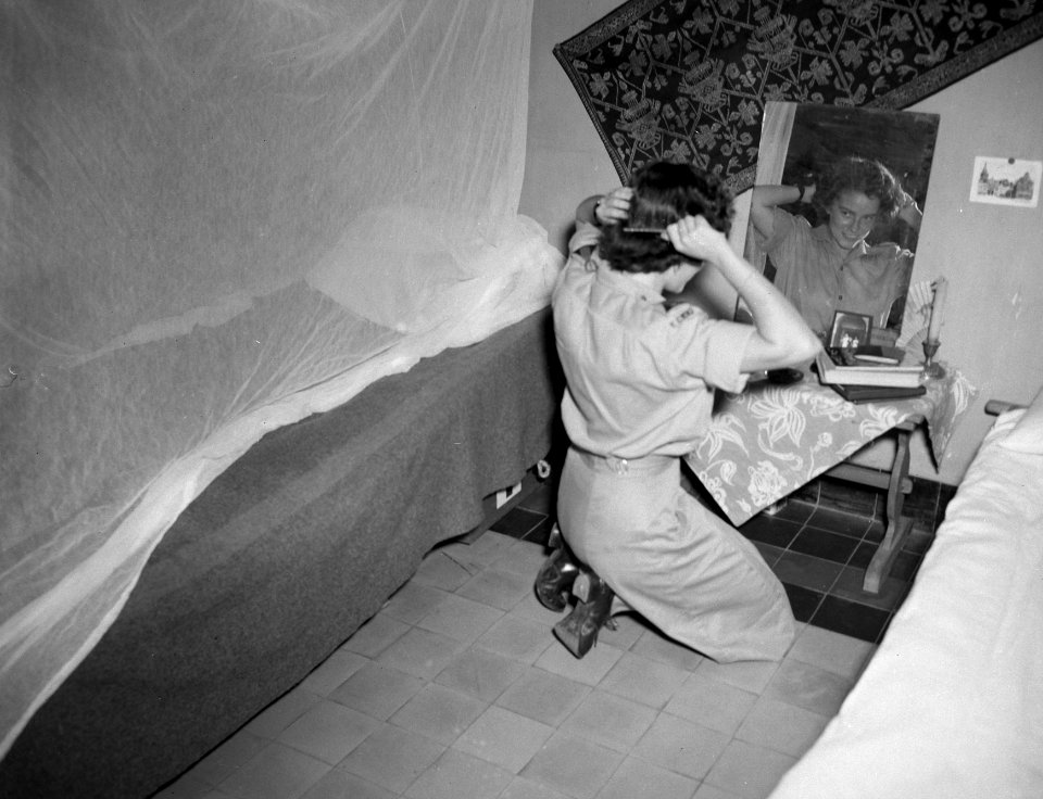 Een lid van het Vrouwenkorps KNIL kamt haar haar voor een spiegel, Bestanddeelnr 10585