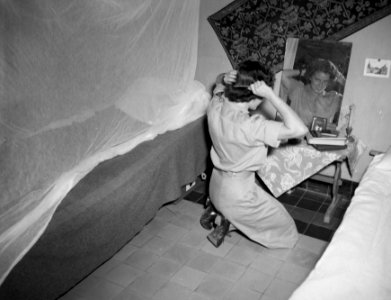 Een lid van het Vrouwenkorps KNIL kamt haar haar voor een spiegel, Bestanddeelnr 10585