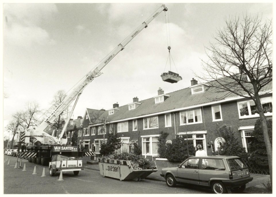 Een kraanwagen aan het werk in de Van Nesstraat, om de achtertuin van de fam. Van der Vooren gereed te maken voor de aanleg van een Japanse tuin. NL-HlmNHA 54032236