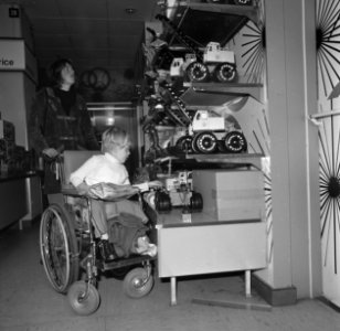 Een kind in een rolstoel bekijkt speelgoed, Bestanddeelnr 926-8398