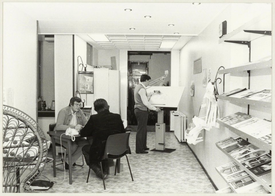 Een kijkje in de Bouwwegwijzer aan de Spaarnwouderstraat 82. Henny Kuvener licht een klant voor over verbouwingsmogelijkheden, Cees Heyboer staat achter de tekentafel. NL-HlmNHA 54011540