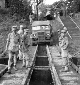 Een legertruck rijdt van een oever een soort veerpont op, Bestanddeelnr 12032