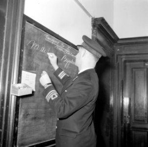 Een luitenant ter zee der 1e klasse schrijft naam op bord onder titel Transport, Bestanddeelnr 255-9475