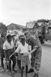 Een militair fouilleert een Indonesisch jongetje, Bestanddeelnr 177-5-1