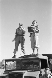 Een militair met microfoon en een militair met clipboard staan op de cabine van , Bestanddeelnr 247-1-4