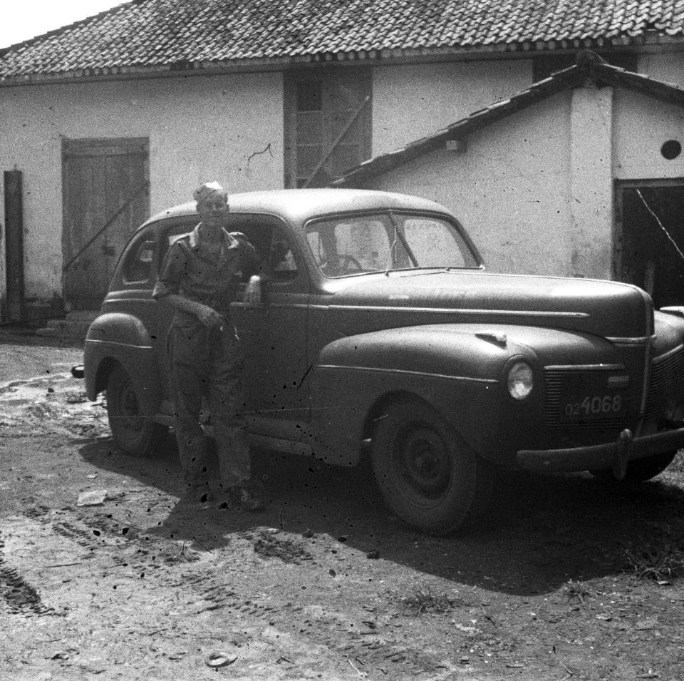 Een militair poseert bij een stafauto, Bestanddeelnr 6968