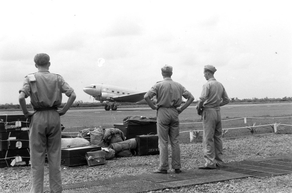 Een militair vliegtuig (een Dakota) landt of stijgt op. In de voorgrond militair, Bestanddeelnr 376