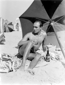 Een man Farrar op het Scheveningse strand onder een parasol, Bestanddeelnr 190-1019