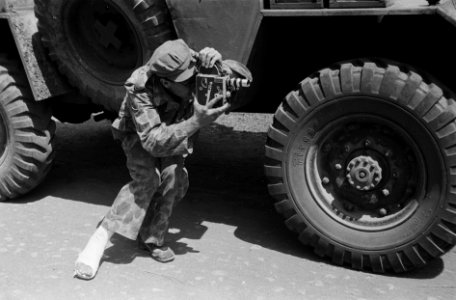 Een militair in camouflagepak (oorlogscorrespondent) - en met zijn voet in het…, Bestanddeelnr 1570