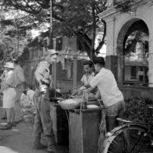 Een militair koopt eten bij een eetstalletje in Batavia, Bestanddeelnr 255-8263