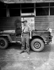 Een man in uniform (zonder distinctieven) staat bij een jeep, Bestanddeelnr 10488