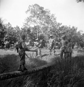 Een militair loopt over een boomstam richting andere soldaten die al aan de ove…, Bestanddeelnr 15820