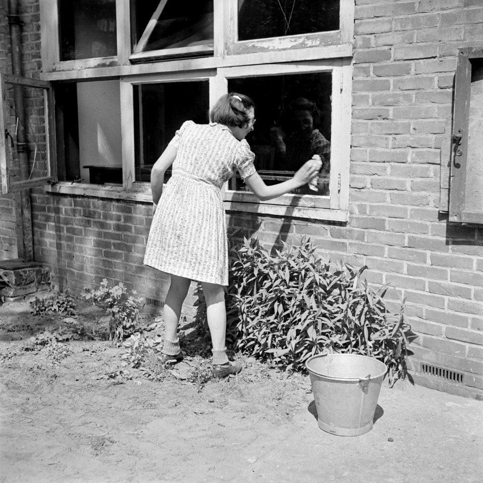 Een leerlinge zeemt de ramen van het schoolgebouw, Bestanddeelnr 255-7376