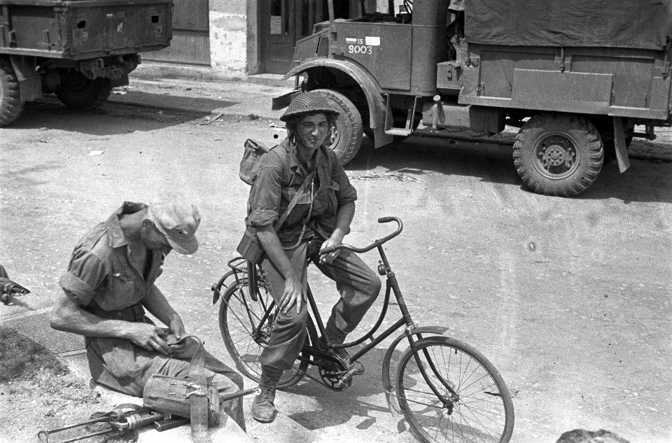 Een militair op een fiets Naast hem verzorgt een zittende militair zijn uitrusting, Bestanddeelnr 5261