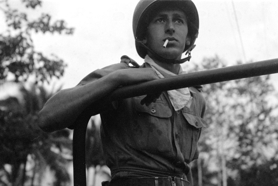 Een Nederlandse militair met helm en shawl en een sigaret in zijn mond staat in , Bestanddeelnr 3255