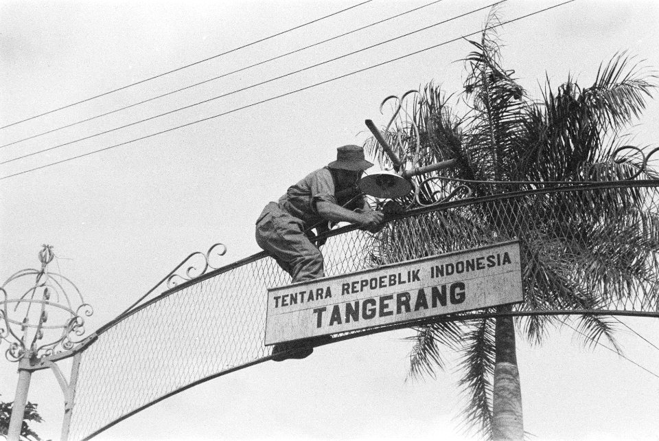 Een Nederlandse militair beklimt een poort om een bord met met de tekst Tentar…, Bestanddeelnr 6-3-1