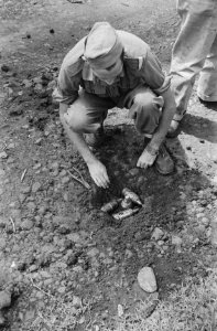 Een Nederlandse militair bij een gat in de grond waarin een aantal landmijnen li, Bestanddeelnr 463-1-6