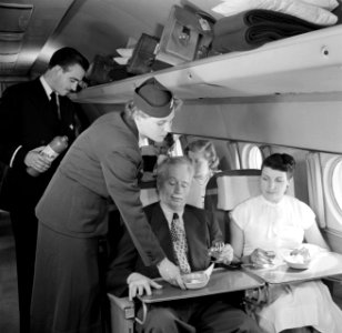 Een passagier in een vliegtuig krijgt zoutjes aangeboden, Bestanddeelnr 252-2061