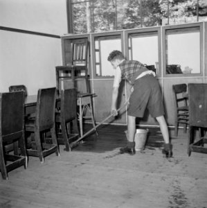 Een leerling schrobt de vloer van een klaslokaal, Bestanddeelnr 255-7375