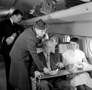 Een passagier in een vliegtuig krijgt zoutjes aangeboden, Bestanddeelnr 252-2060