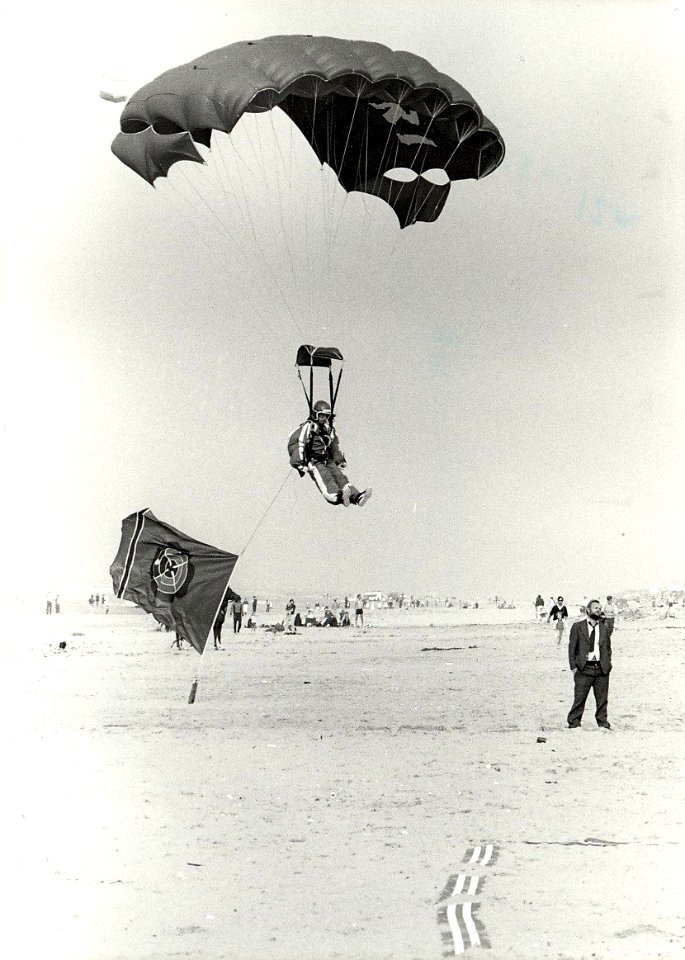 Een parachutist landt met de vlag van het casino op het Zandvoortse strand, i.v.m. het zes-jarig bestaan van het casino. Aangekocht in 1983 van fotograaf C. de Boer. - Negatiefnummer 22373 k, NL-HlmNHA 54013124
