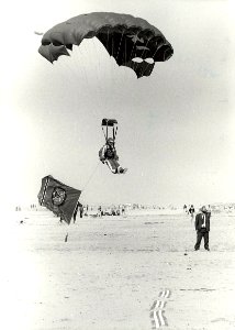 Een parachutist landt met de vlag van het casino op het Zandvoortse strand, i.v.m. het zes-jarig bestaan van het casino. Aangekocht in 1983 van fotograaf C. de Boer. - Negatiefnummer 22373 k, NL-HlmNHA 54013124
