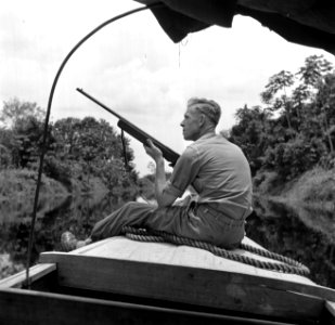 Een reisgezel van fotograaf Willem van de Poll, de heer De Haas, met een geweer…, Bestanddeelnr 252-5657