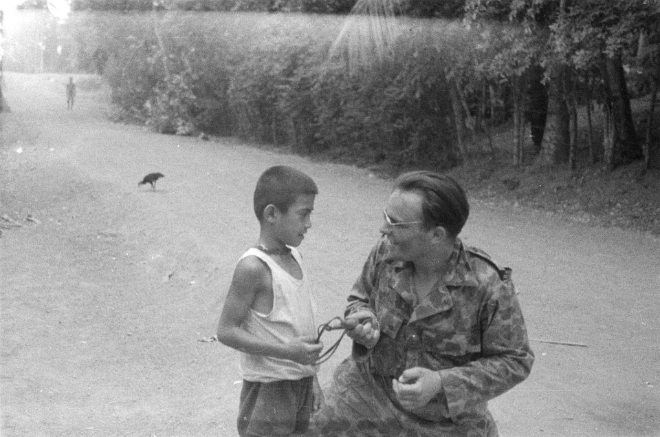 Een Public Relation man leert een Indonesische jongen om te gaan met een katapul, Bestanddeelnr 75-6-1