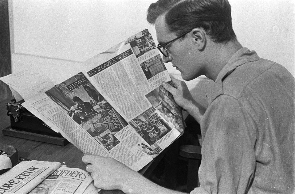 Een redacteur leest een exemplaar van het tijdschrift Wapenbroeders, gezeten aa…, Bestanddeelnr 380-5-6