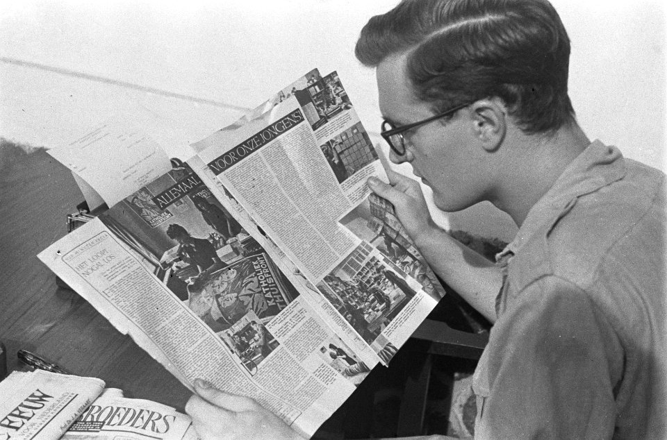 Een redacteur leest een exemplaar van het tijdschrift Wapenbroeders, gezeten aa…, Bestanddeelnr 380-5-5
