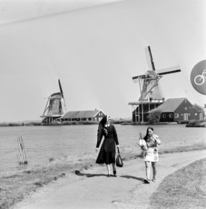 Een paar Noord-Hollandse molens bij een meer Op het voetpad een non en een meis, Bestanddeelnr 928-0836